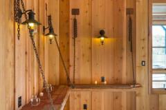 Wood shelves supported by chains are attached to the untreated wood walls.